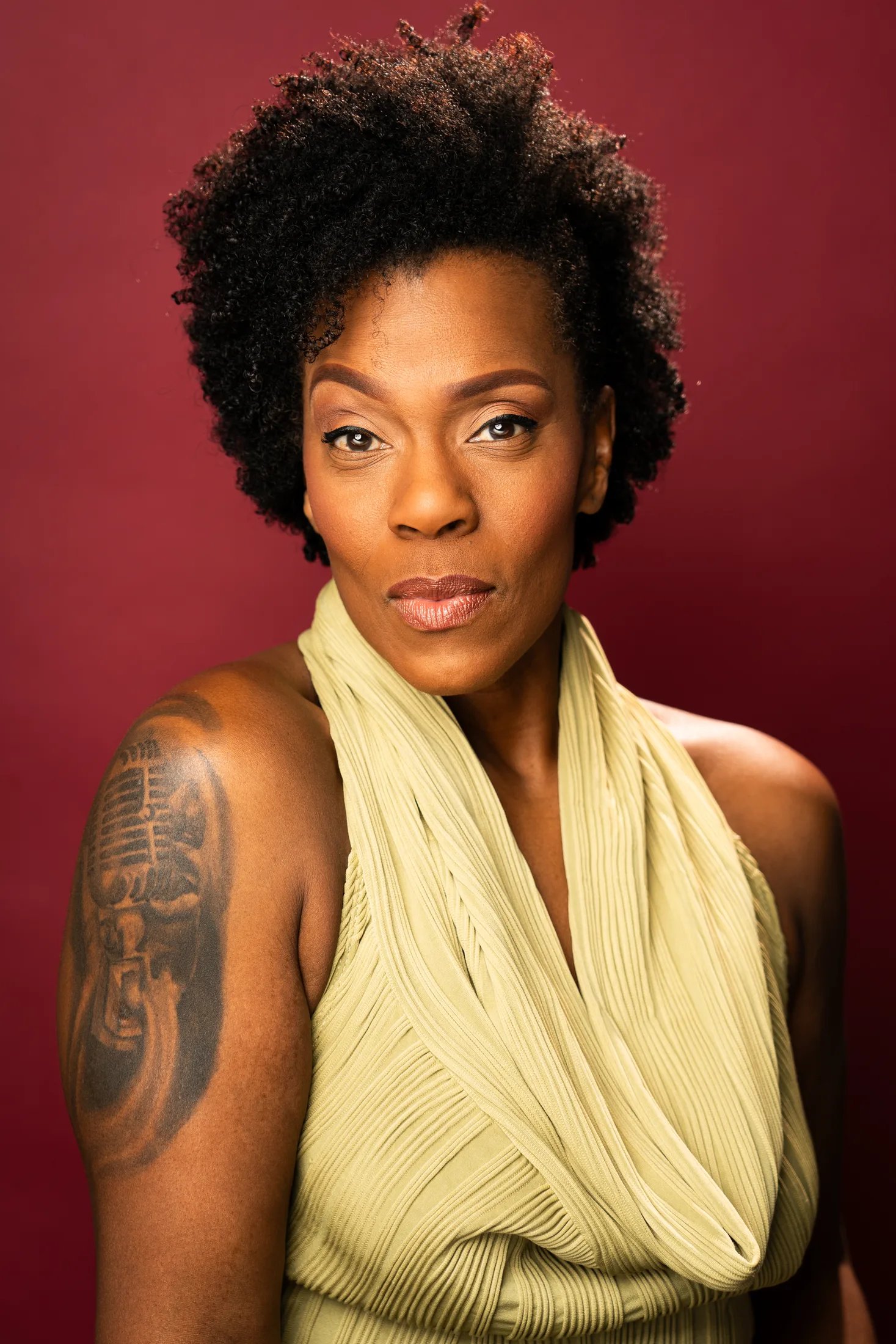Patrece Bloomfield in a green draped top against a red backdrop